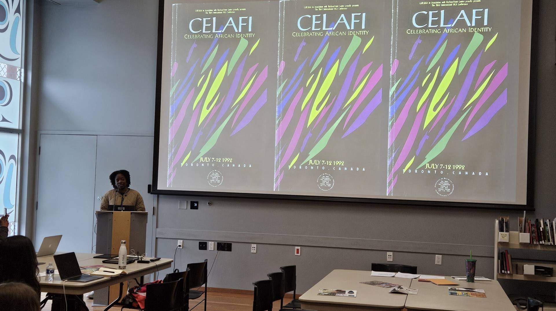 Celebrating African identity poster displayed on a projector screen at an indoor event in Toronto.
