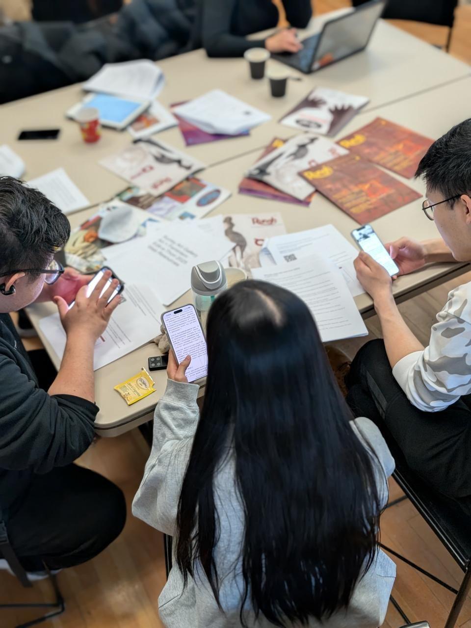 Group of people using smartphones and tablets during a meeting.