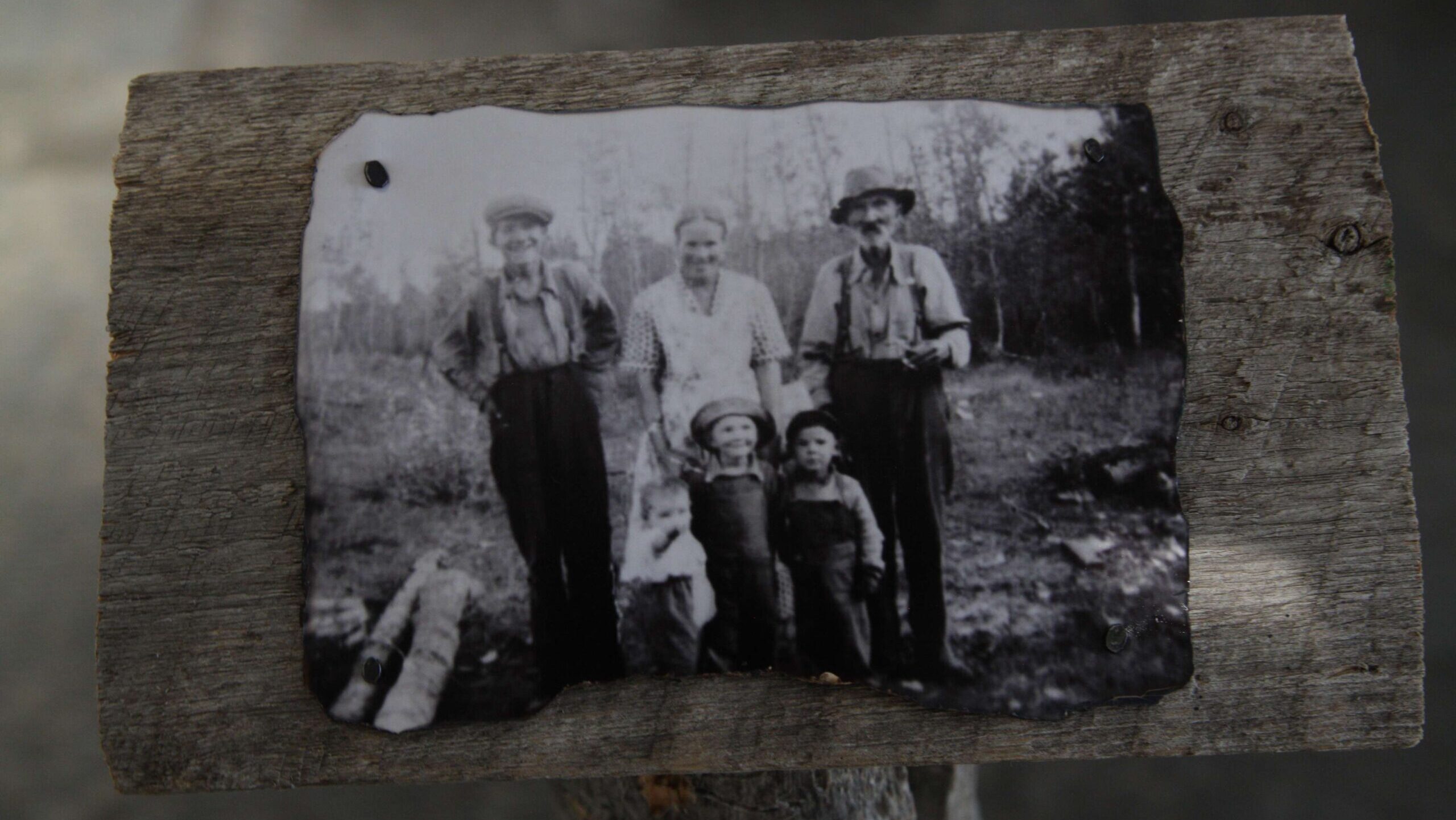 Vintage black and white photo of a family outdoors on a wooden surface.