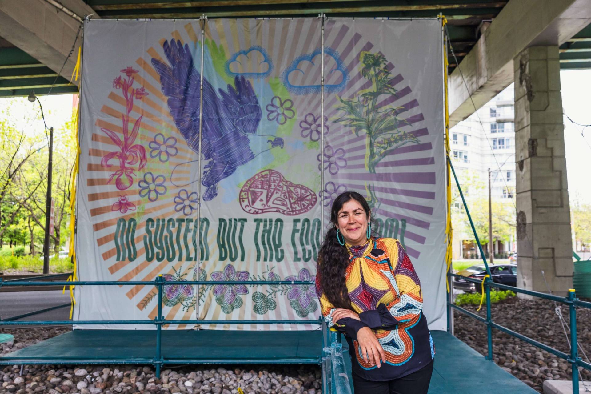 Woman standing in front of a colorful Rungh banner at an outdoor event.
